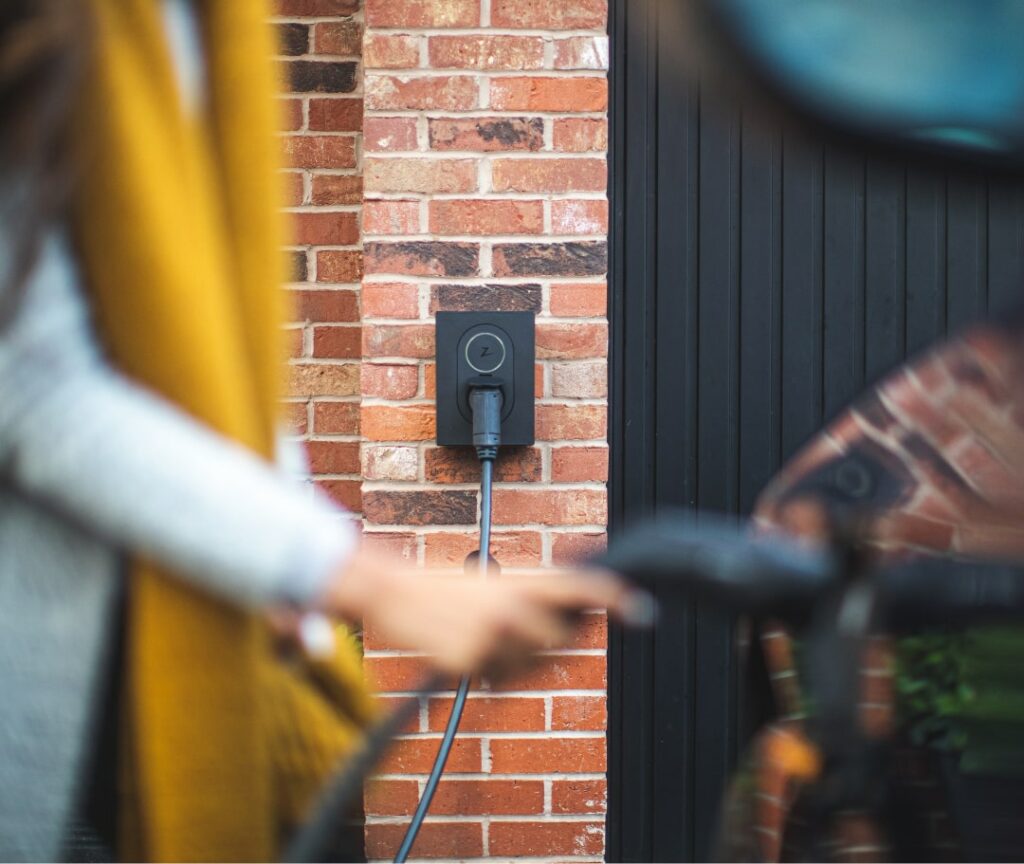 decorative image of a woman plugging her car in at home with an ev4all charger